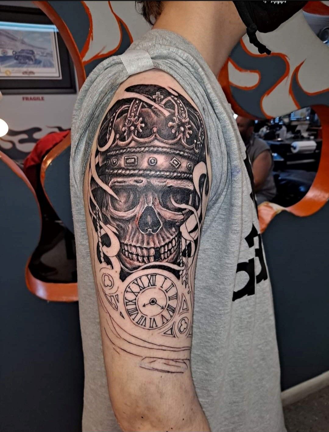 A man has a tattoo of a skull and a clock on his arm