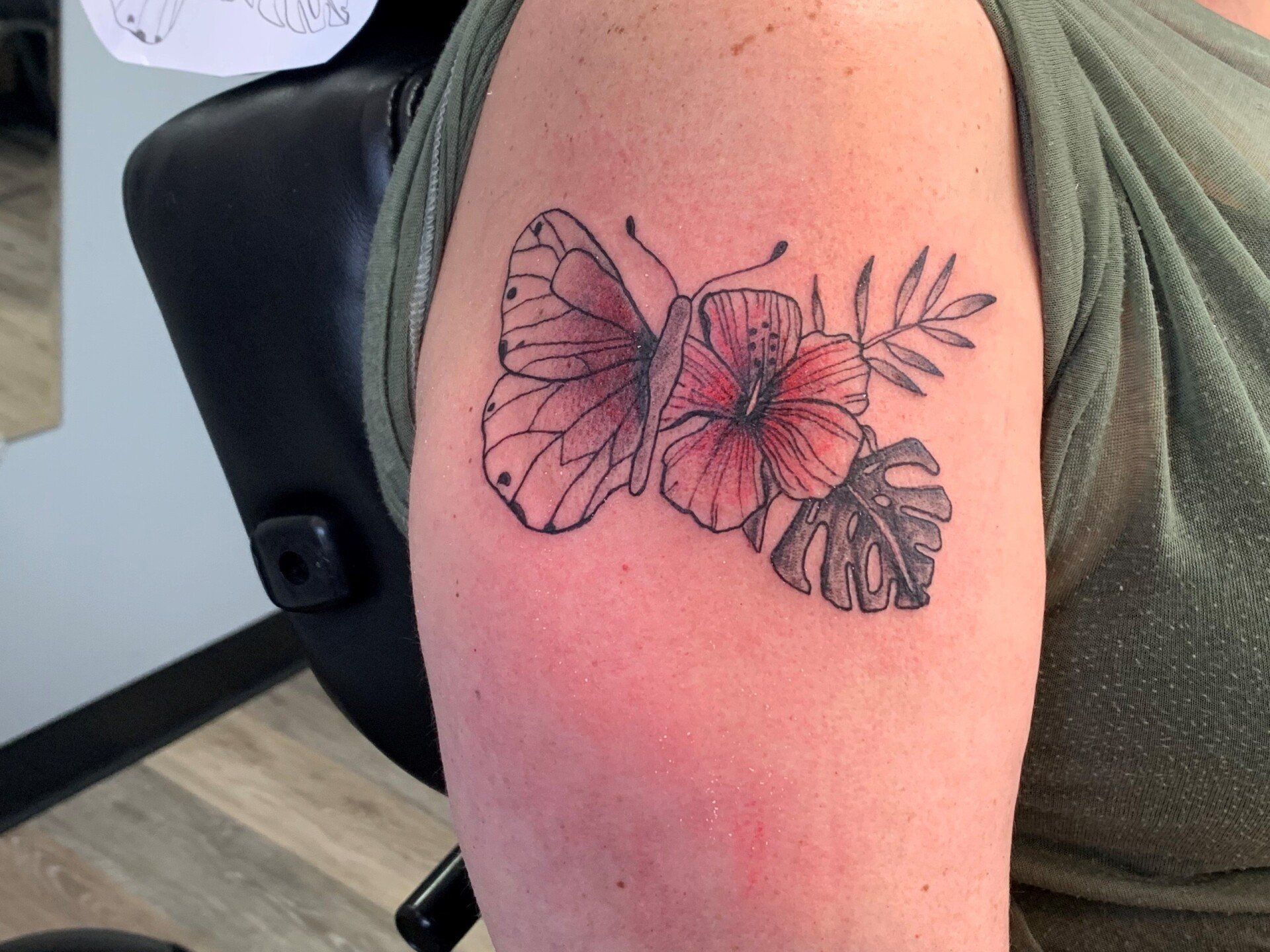 A woman has a tattoo of a butterfly and flowers on her arm.