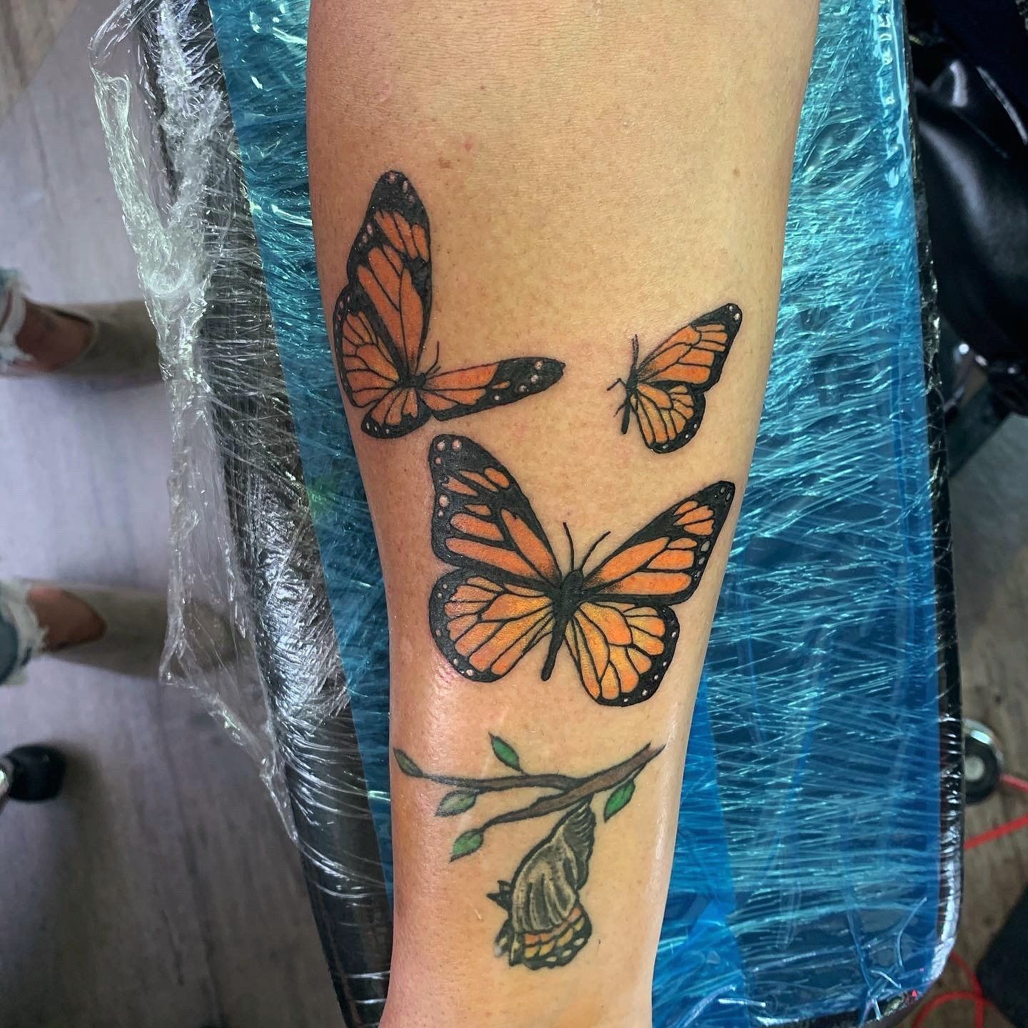 A woman has a tattoo of three butterflies on her forearm.