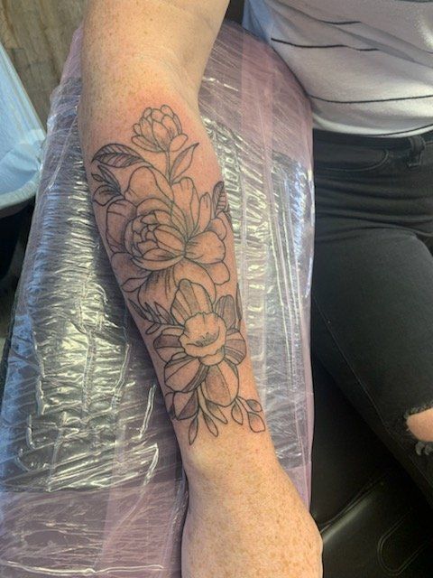 A woman has a tattoo of flowers on her forearm