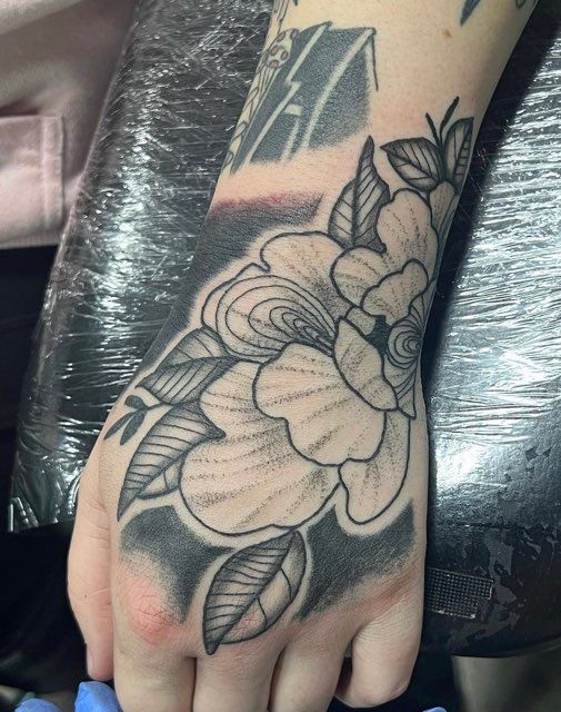 A person has a tattoo of a flower on their hand