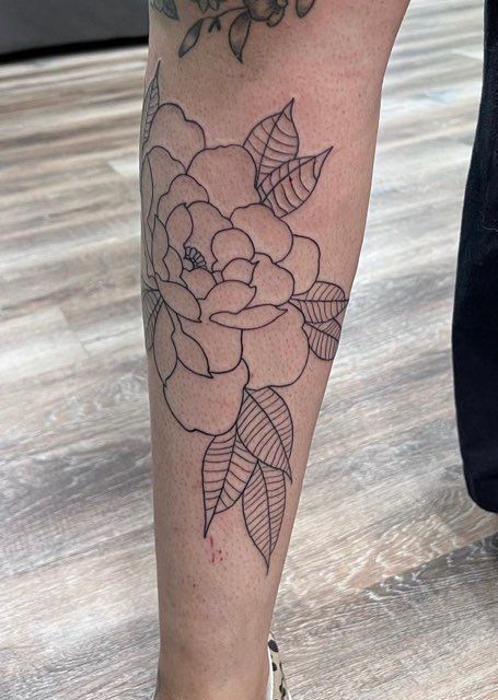 A person has a tattoo of a rose on their leg.