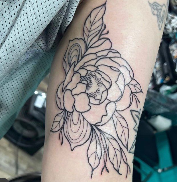 A black and white tattoo of a flower on a person 's arm