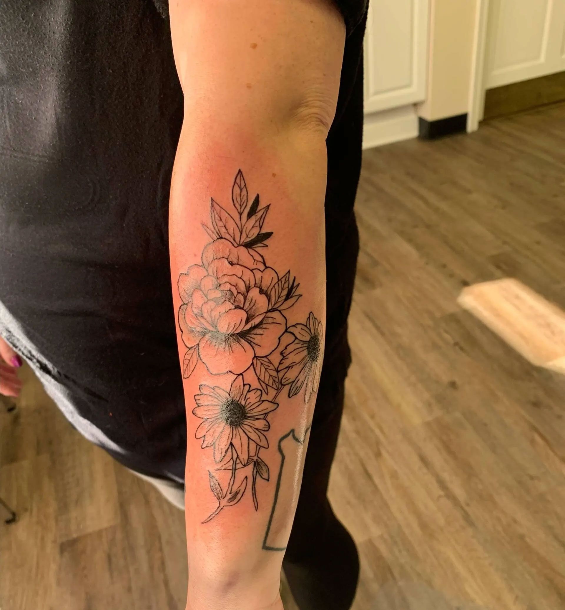 A woman has a tattoo of flowers on her arm.