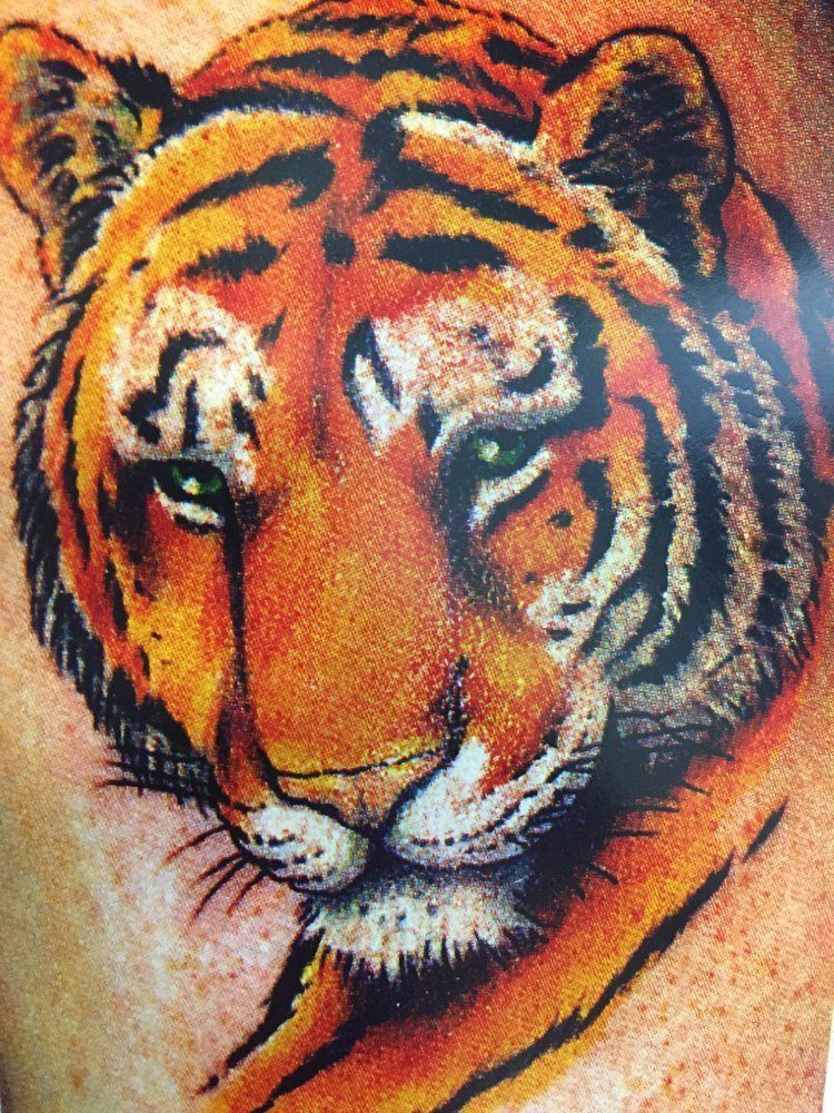 A close up of a tattoo of a tiger 's head