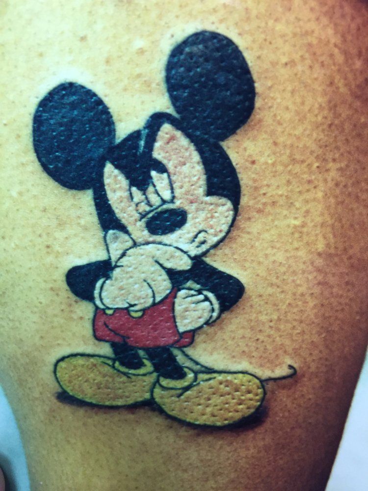 A person has a tattoo of mickey mouse on their leg