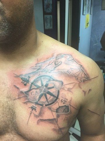 A man has a tattoo of a compass on his chest.