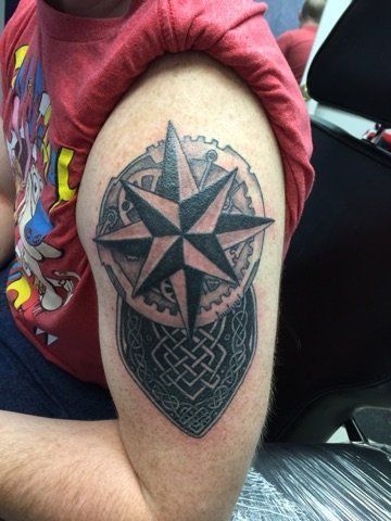 A man has a tattoo of a compass on his arm.