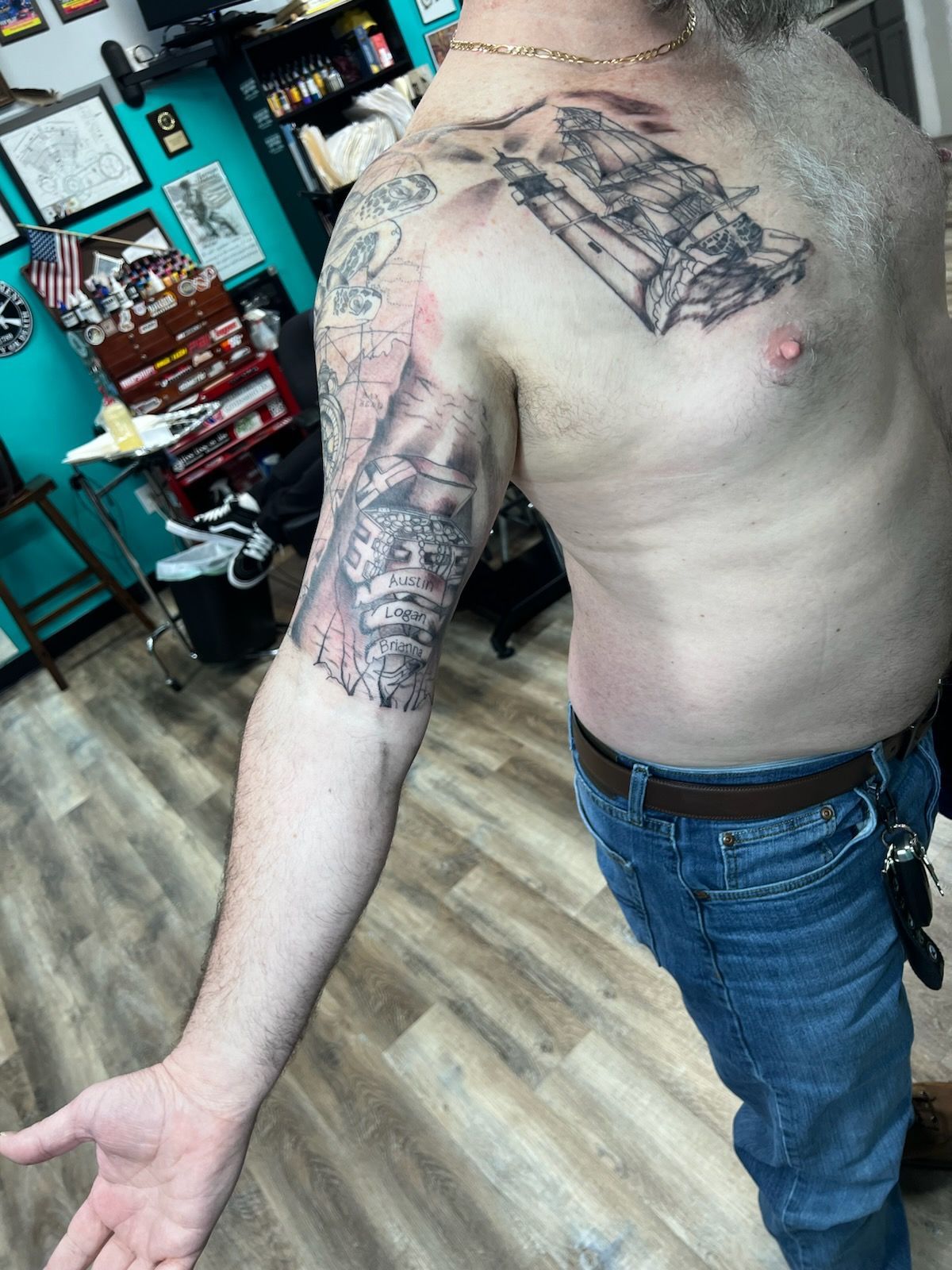 A shirtless man with a tattoo on his arm and chest.