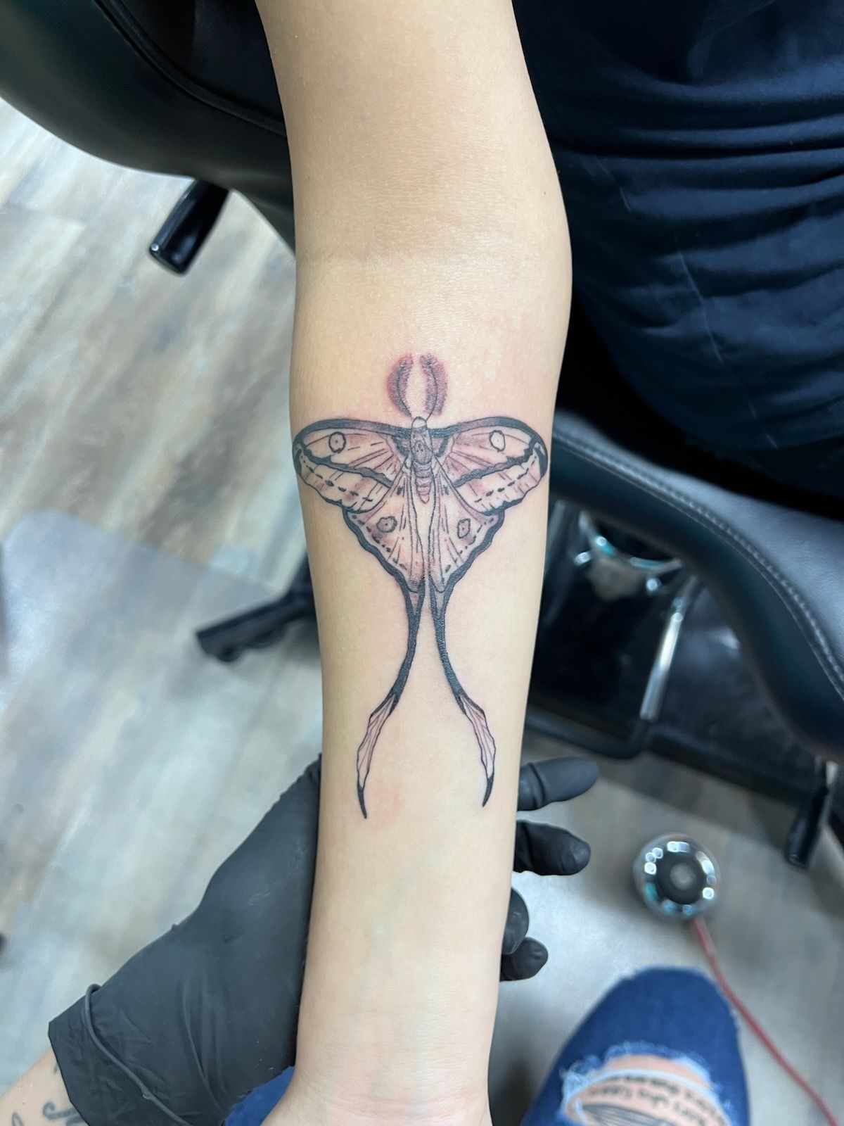 A person has a tattoo of a moth on their wrist.