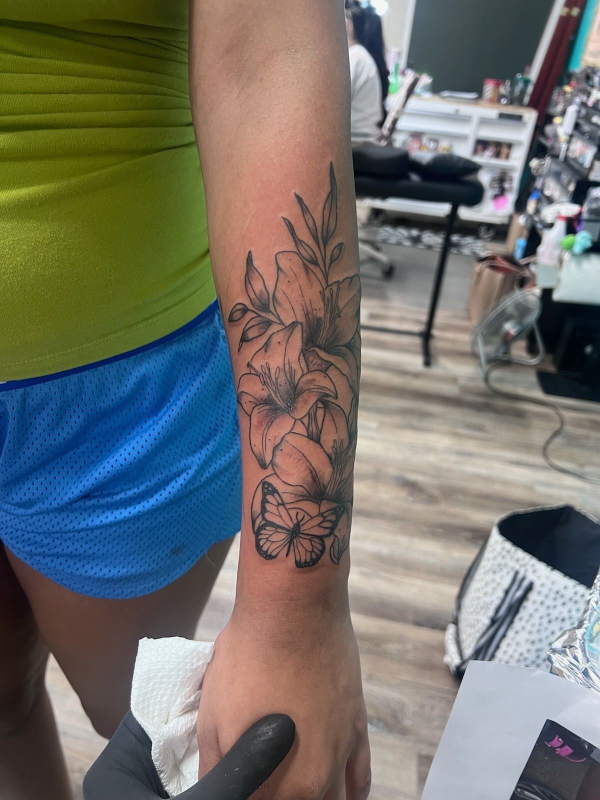 A woman has a tattoo of flowers and butterflies on her forearm.