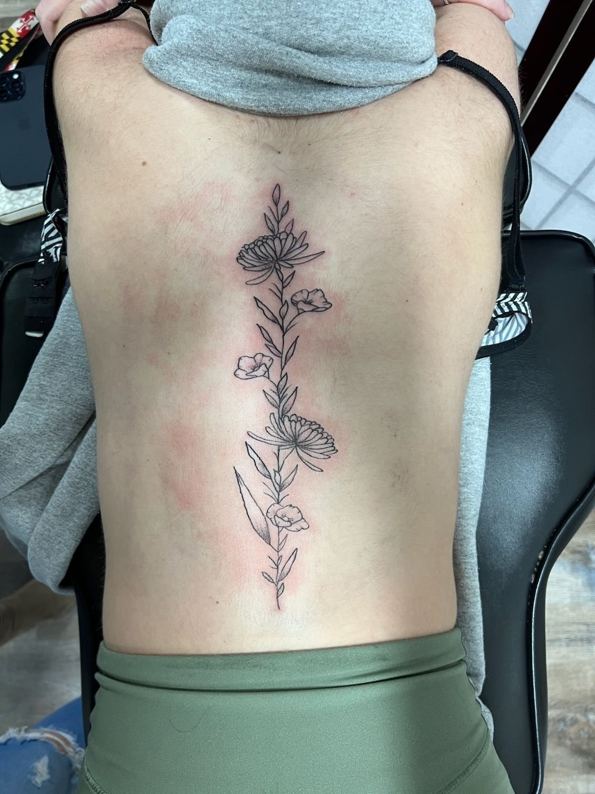A woman has a tattoo on her back of flowers.