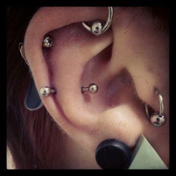 A close up of a person 's ear with a lot of piercings