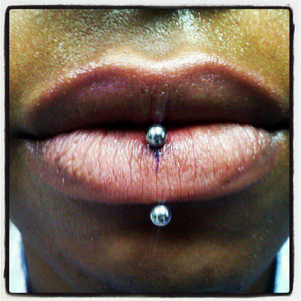 A close up of a woman 's lips with a lip piercing