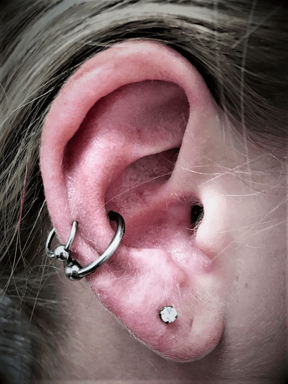 A close up of a woman 's ear with multiple piercings.