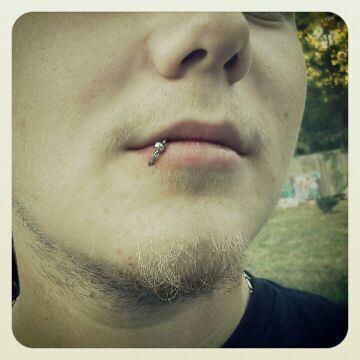 A close up of a man 's face with a piercing in his lip