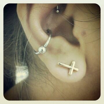 A close up of a woman 's ear with a cross earring