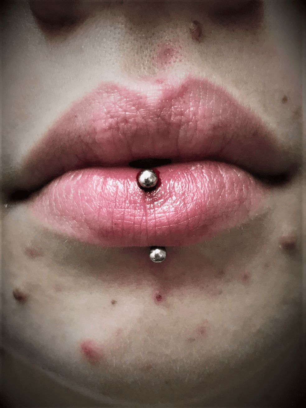 A close up of a woman 's lips with a lip piercing.