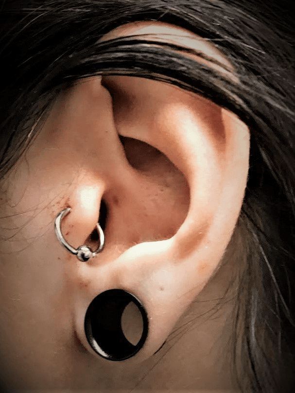 A close up of a woman 's ear with multiple piercings