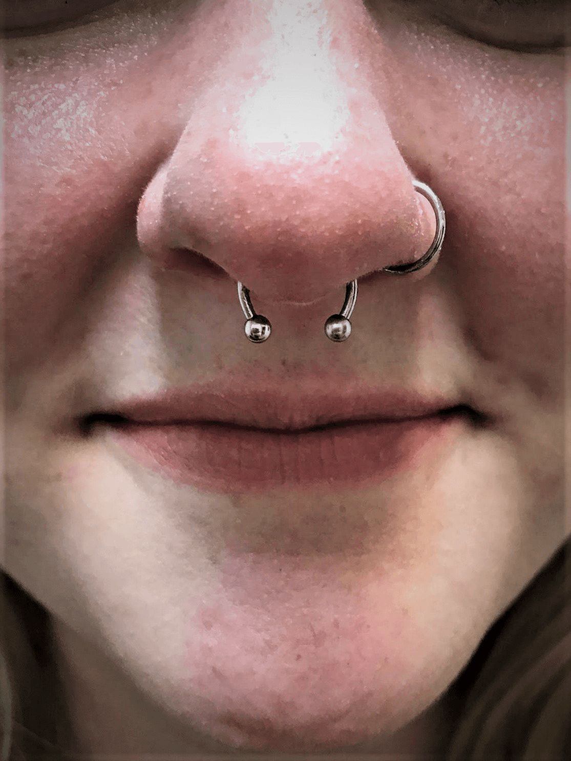 A close up of a woman 's face with a nose ring.