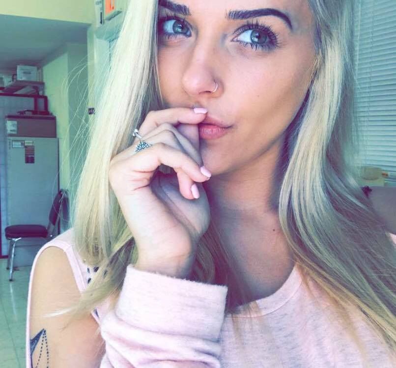 A woman with blonde hair is holding her hand to her mouth