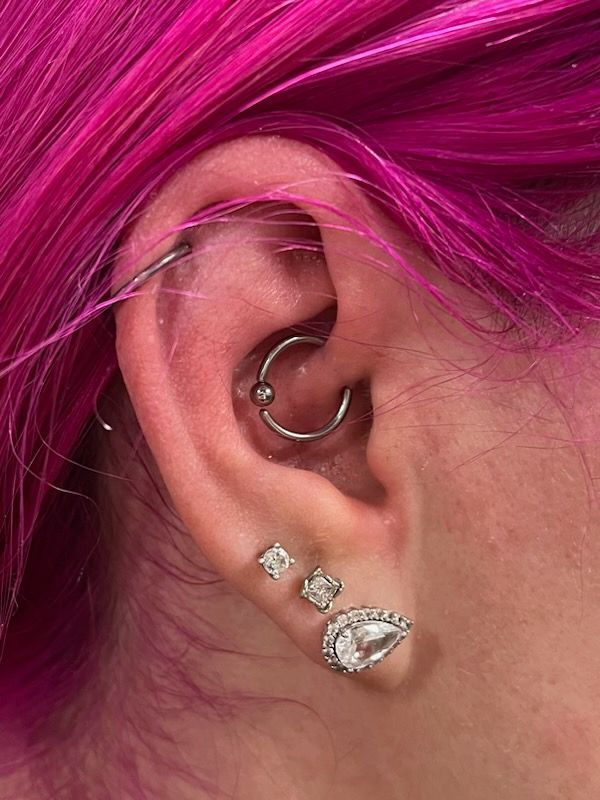 A close up of a woman 's ear with multiple piercings.