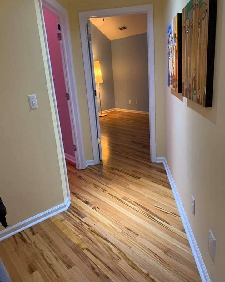 A hallway with hardwood floors and paintings on the wall.