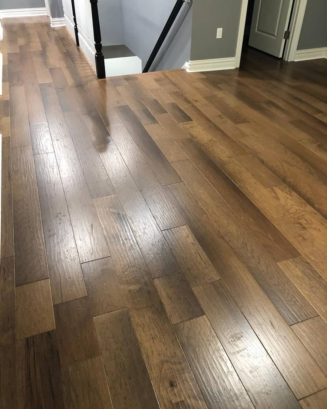 A wooden floor in a room with stairs in the background.