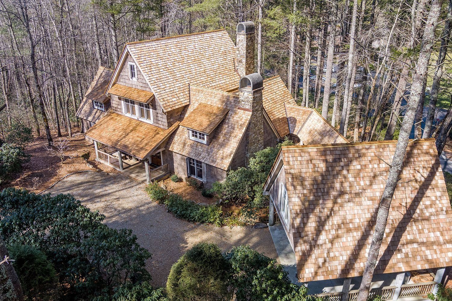 House with cedar shake roof surrounded by trees.