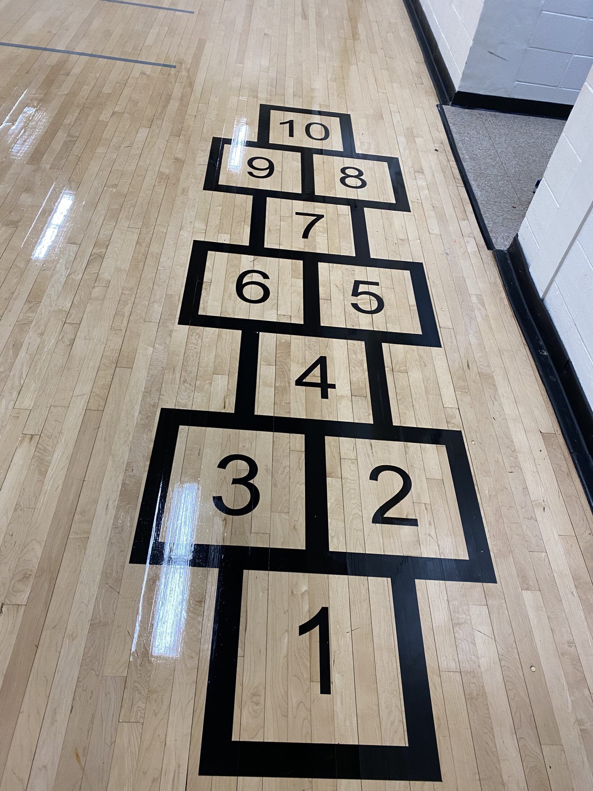 Hopscotch court painted on a wooden floor with numbers 1 through 10.