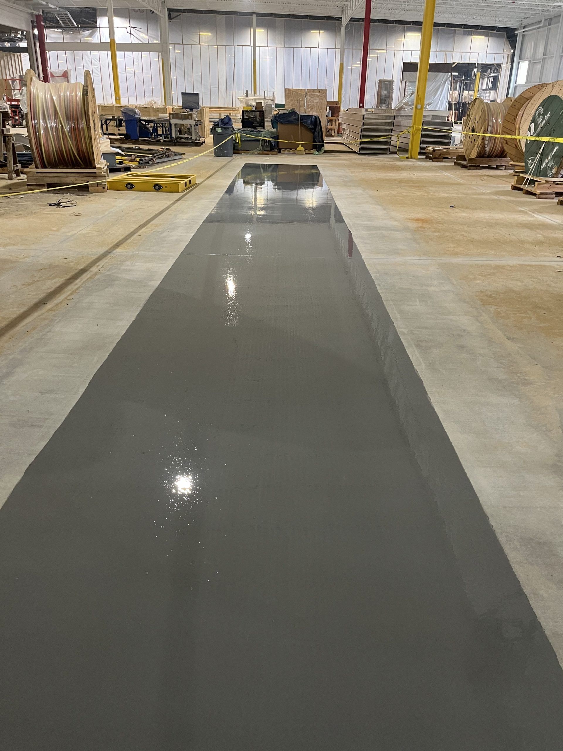 Newly painted gray concrete floor in an industrial warehouse setting.