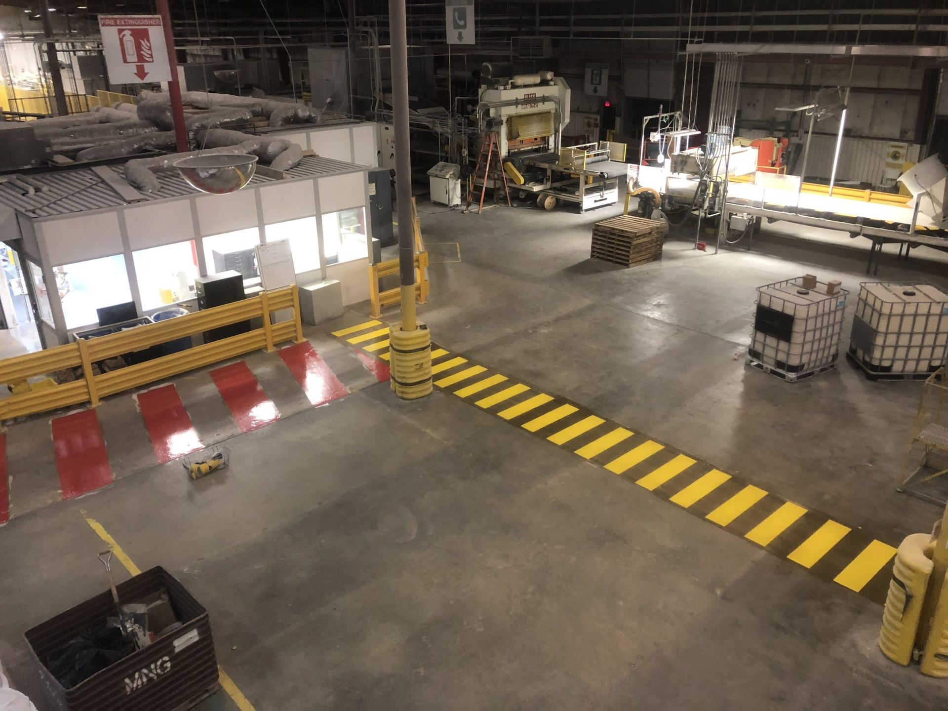 Overhead view of a factory floor with yellow and black crosswalk markings and industrial equipment.