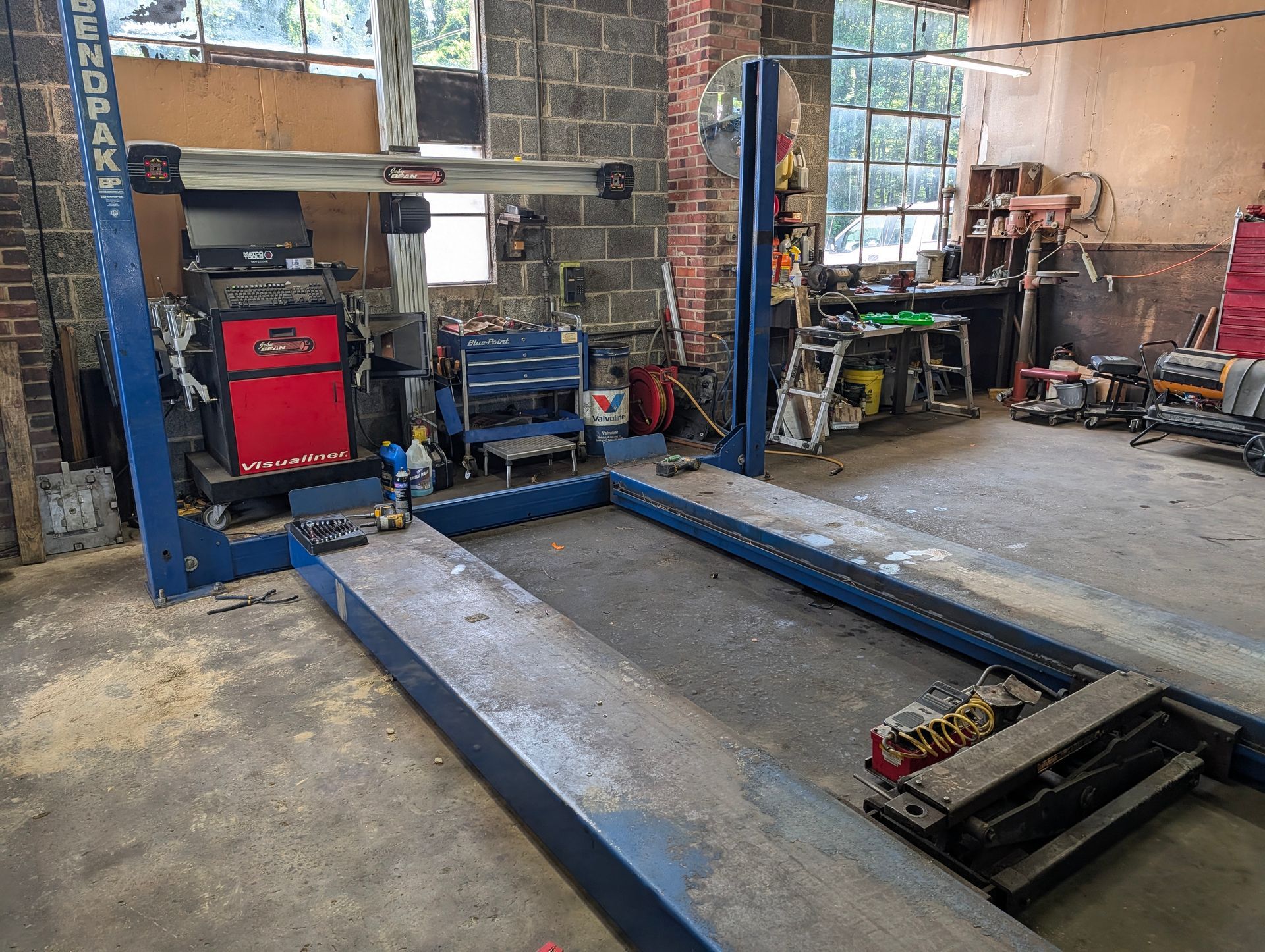 Auto repair shop with a blue car lift, tools, and equipment in a garage.