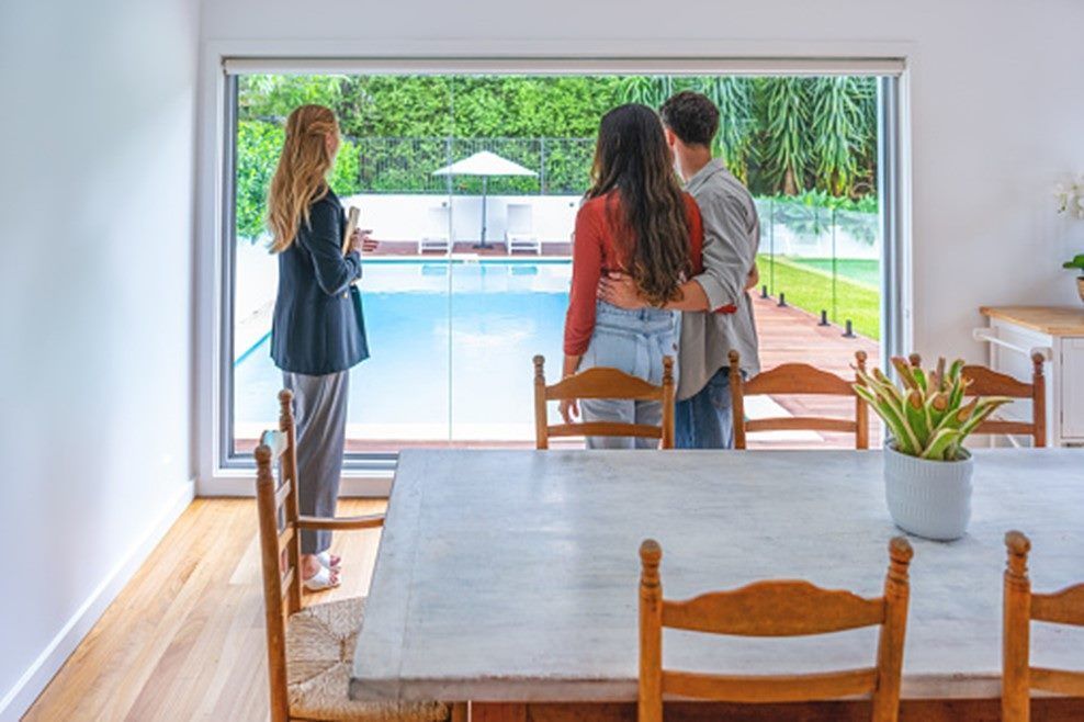 A family is looking out of a window at a swimming pool.