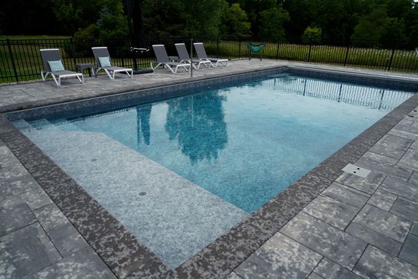 A large swimming pool surrounded by chairs and a fence.