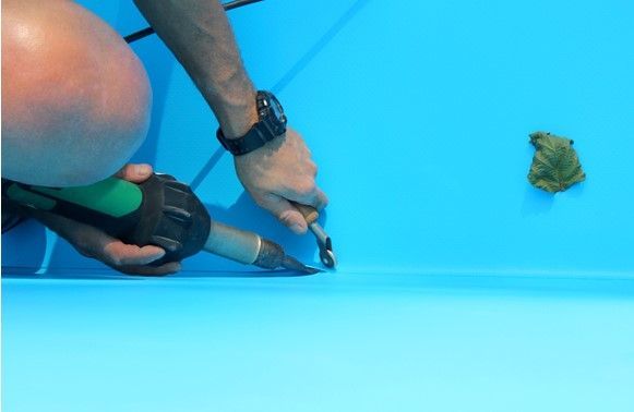 A man is using a tool on a blue surface.