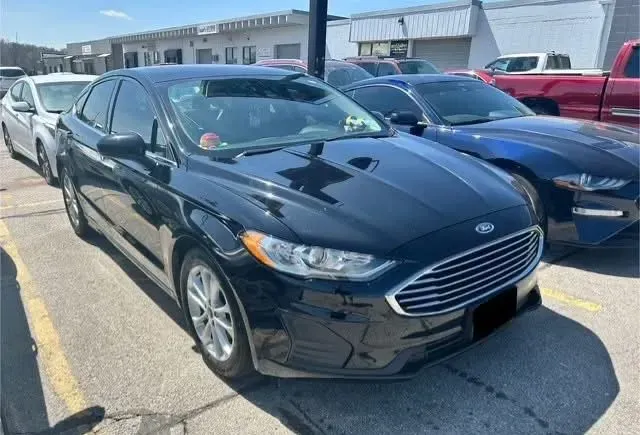 Black Ford Fusion parked in a lot, other vehicles visible.