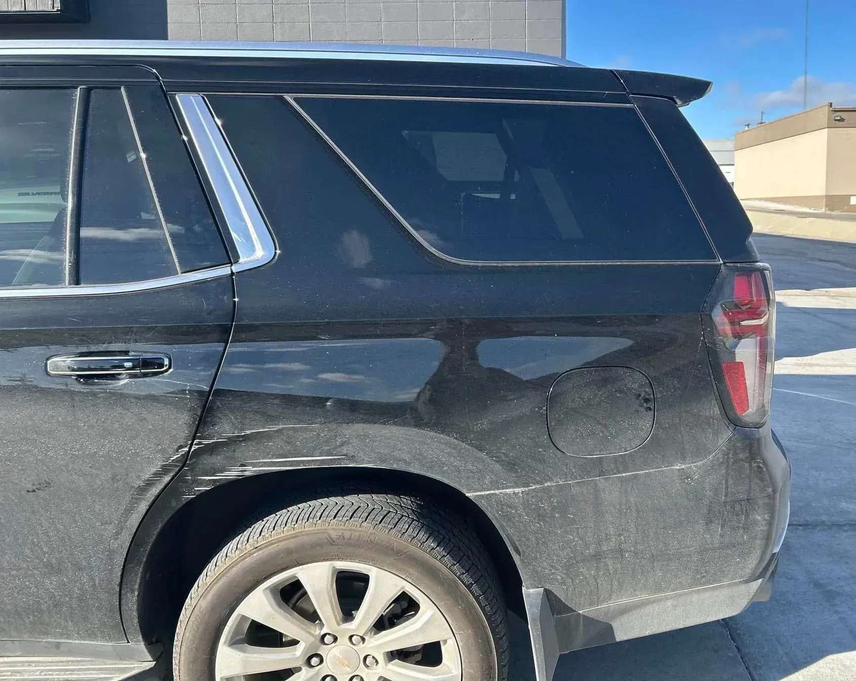 Black SUV parked outside, side view. Dusty, with chrome trim and tinted windows.