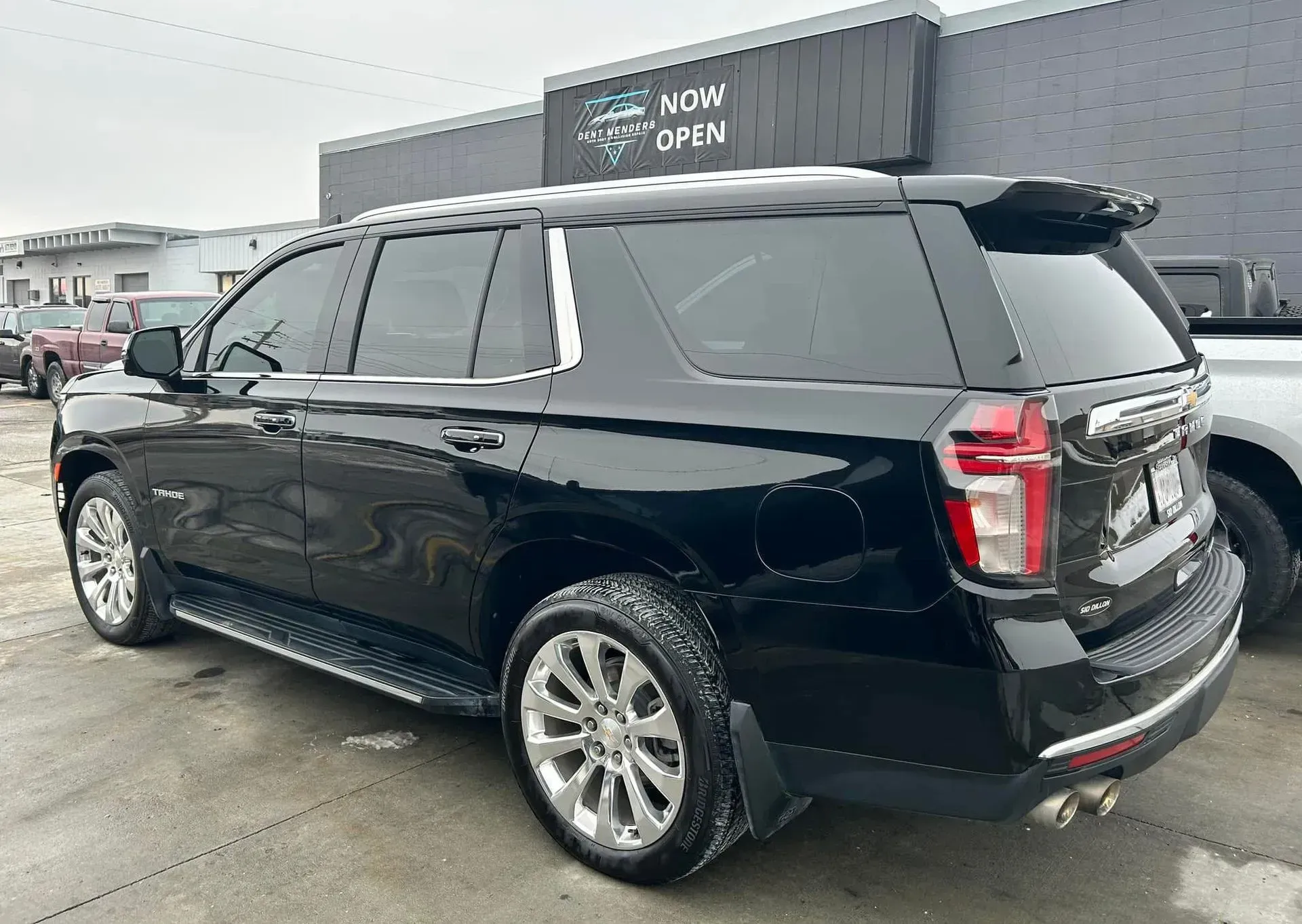 Black Chevrolet Tahoe SUV parked outside a car dealership with a 