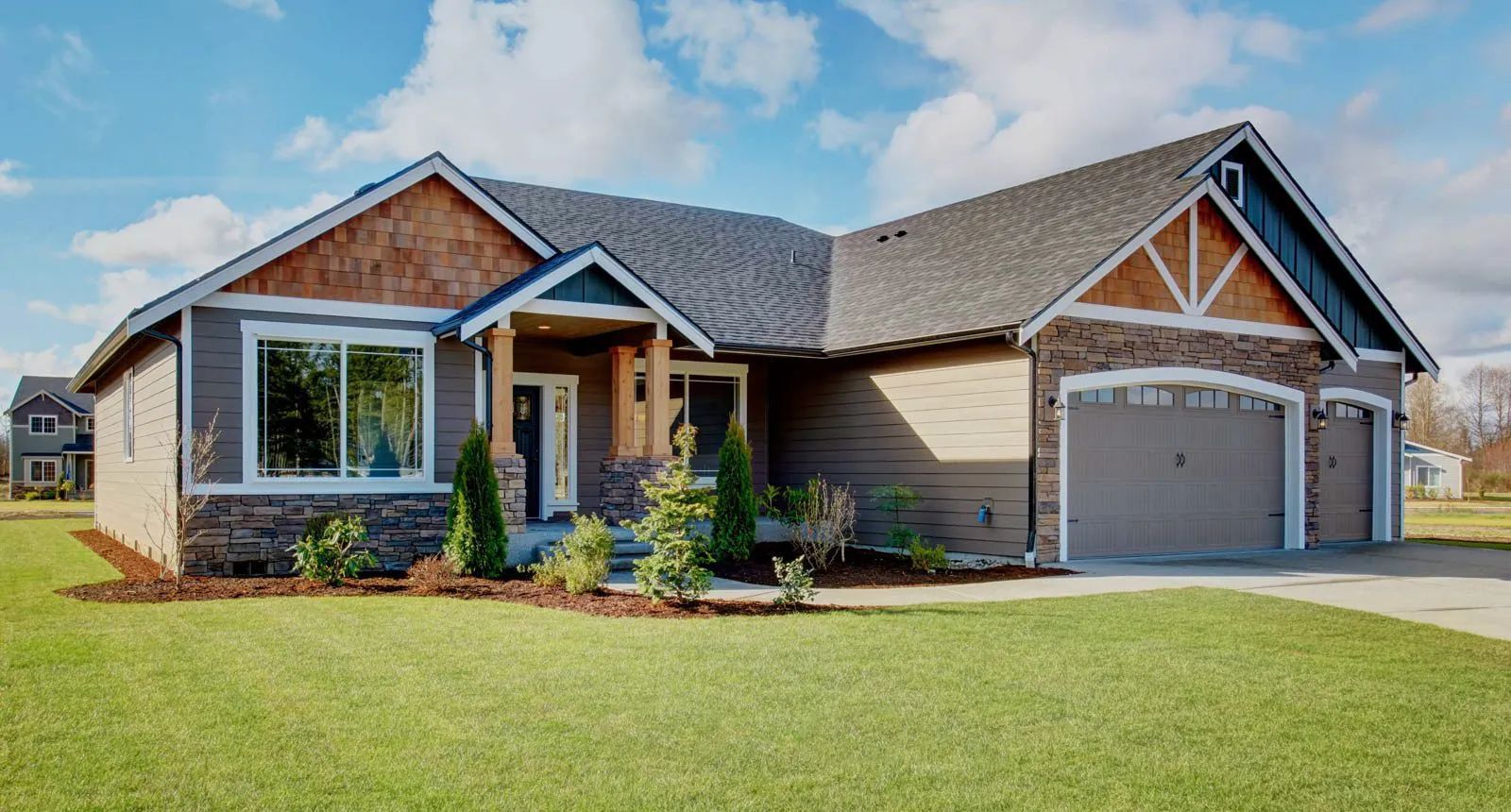Single-story brick house with a two-car garage and a manicured front lawn under a clear sky