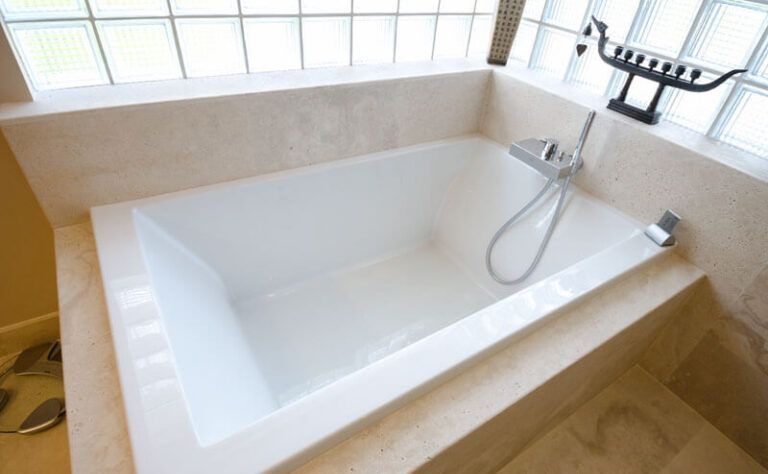 A white bathtub with a shower head in a bathroom.
