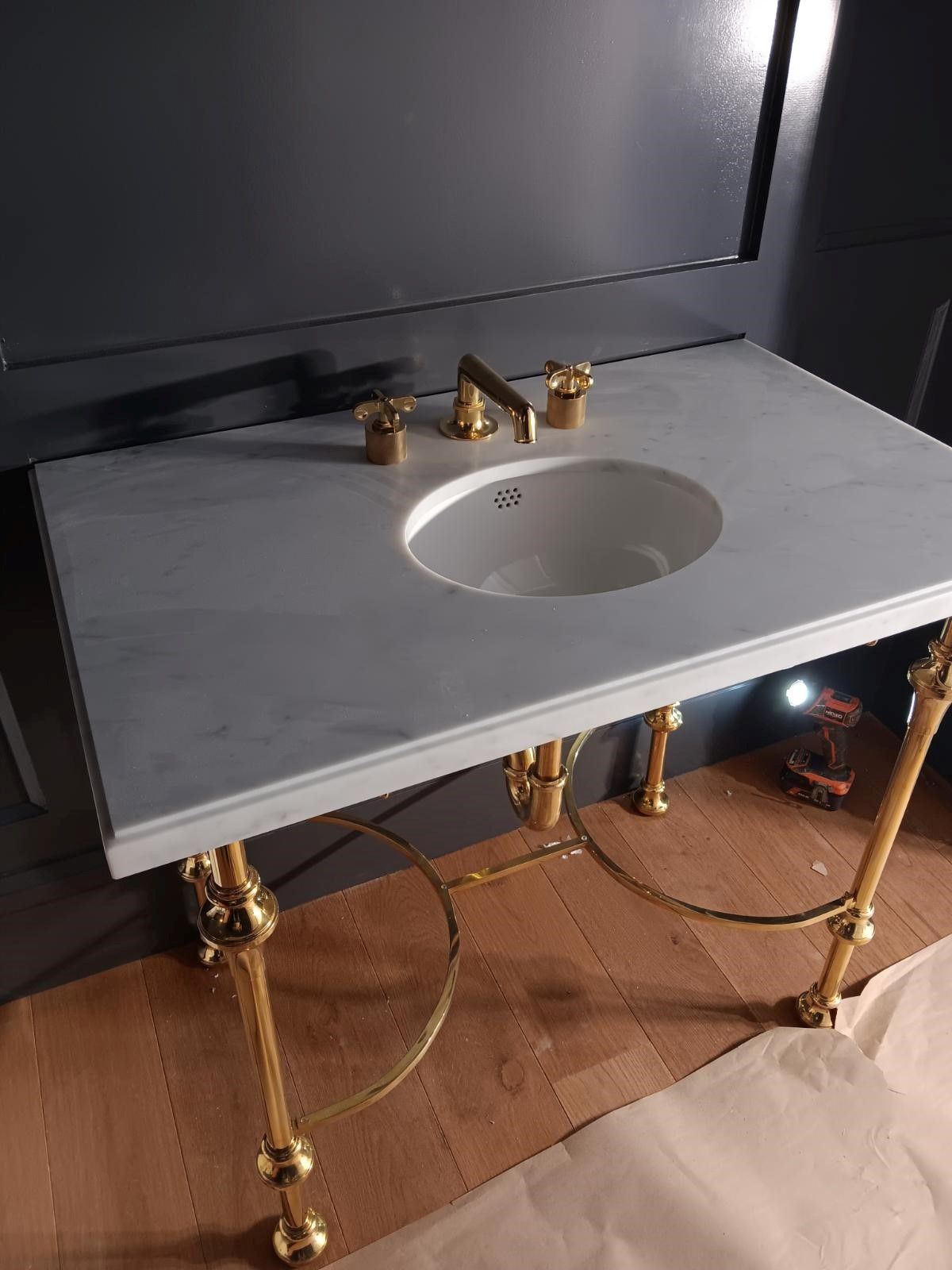 A bathroom sink with a marble counter top and gold legs