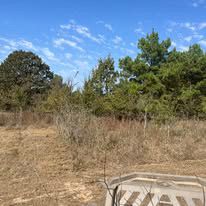 There is a fence in the middle of a field with trees in the background.
