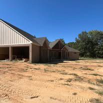A large house is sitting in the middle of a dirt field.