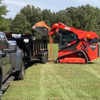 A bulldozer is loading dirt into a dump truck.