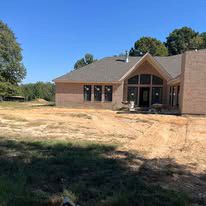 A large brick house is sitting in the middle of a dirt field.