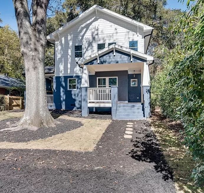 Two people in hard hats and safety vests examining blueprints at a construction site with surveying equipment.