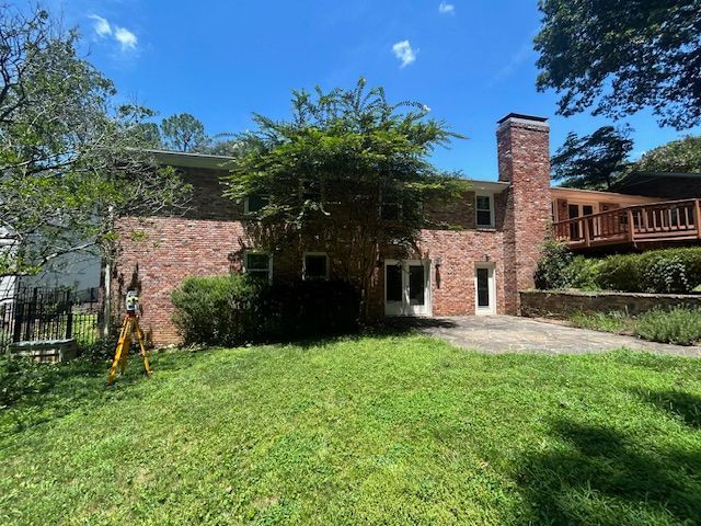 Surveyor in orange vest using a theodolite on a tripod. Blue sky background.