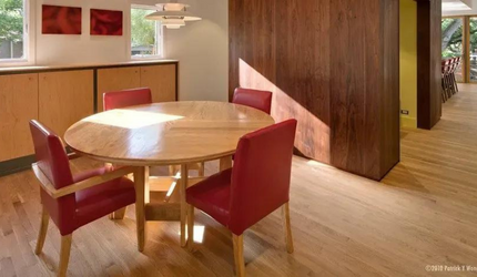 A dining room with a round table and red chairs