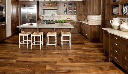 A kitchen with wooden floors and stools and a large island.